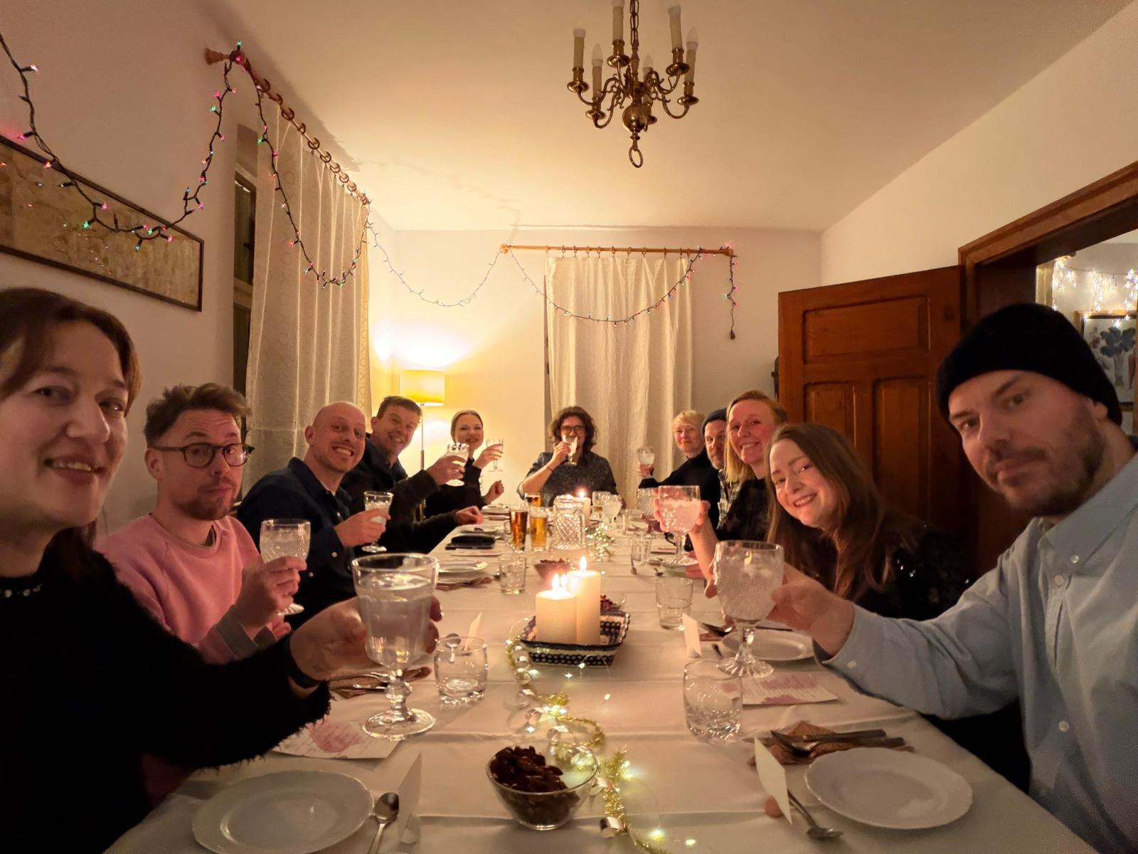 A group raising a toast at the long candlelit dining table at Domstolat
