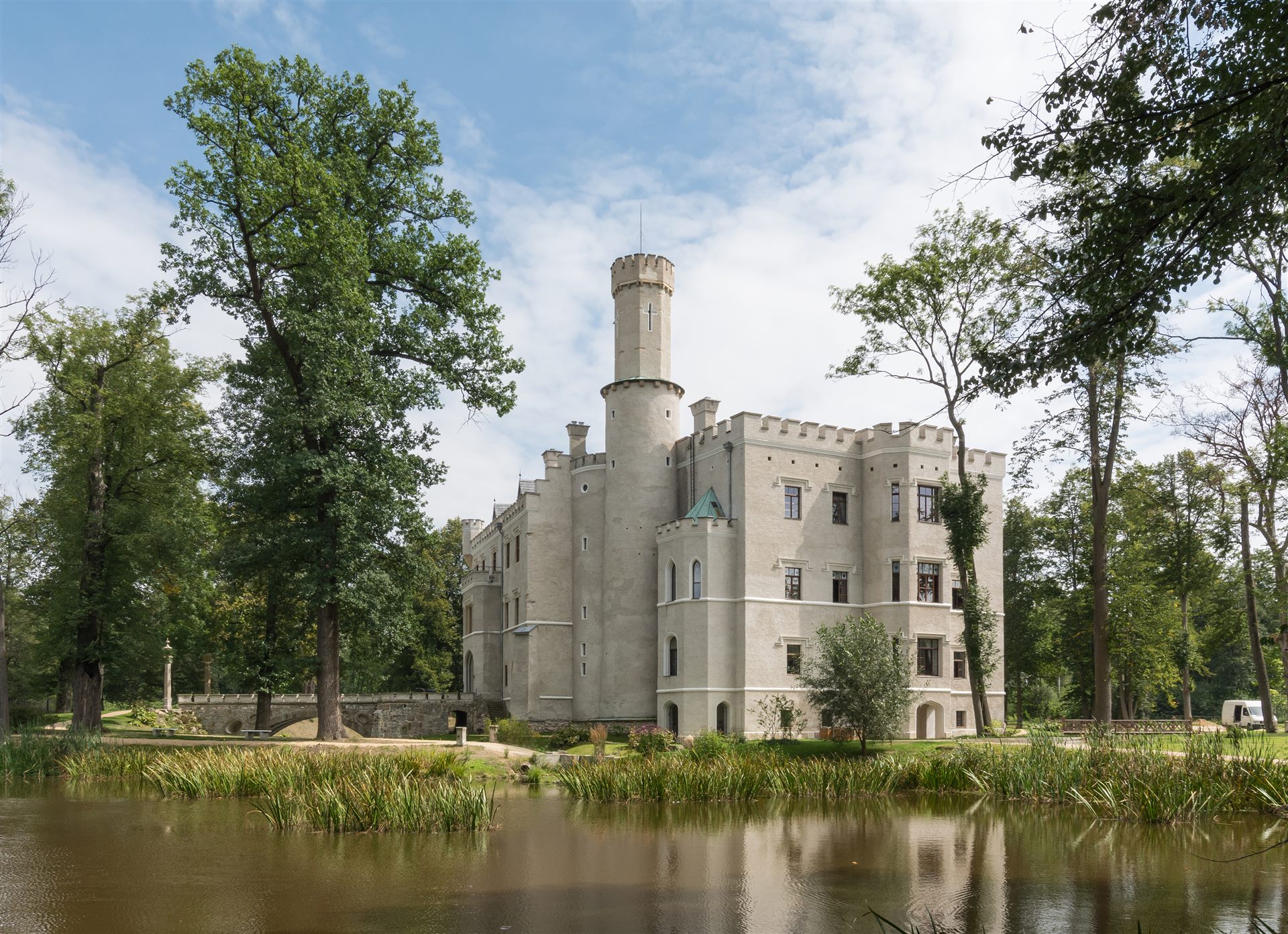 Das neugotische Wasserschloss Karpniki spiegelt sich im Teich