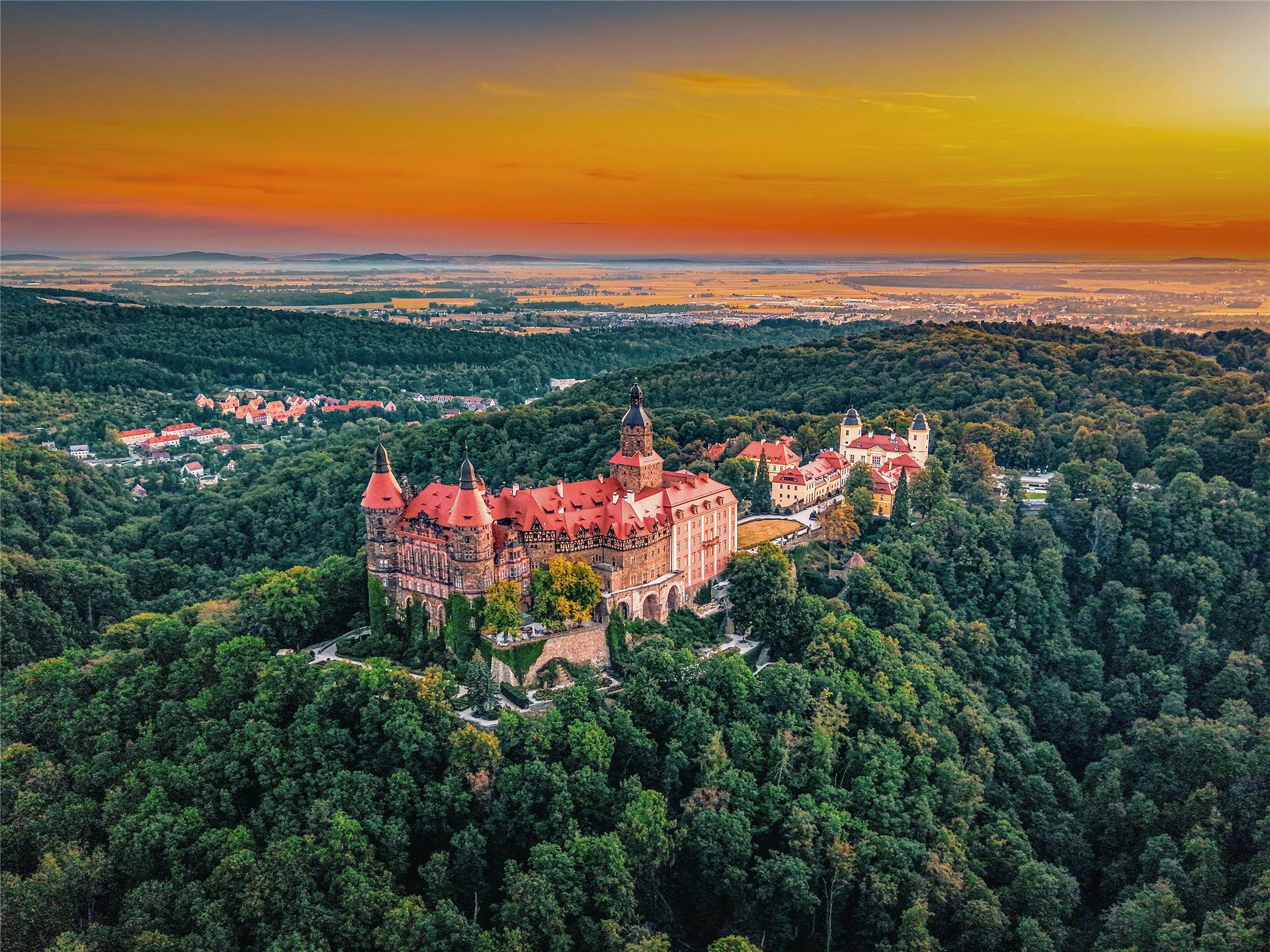 Schloss Książ auf dem bewaldeten Hügel bei Sonnenaufgang, aus der Luft gesehen