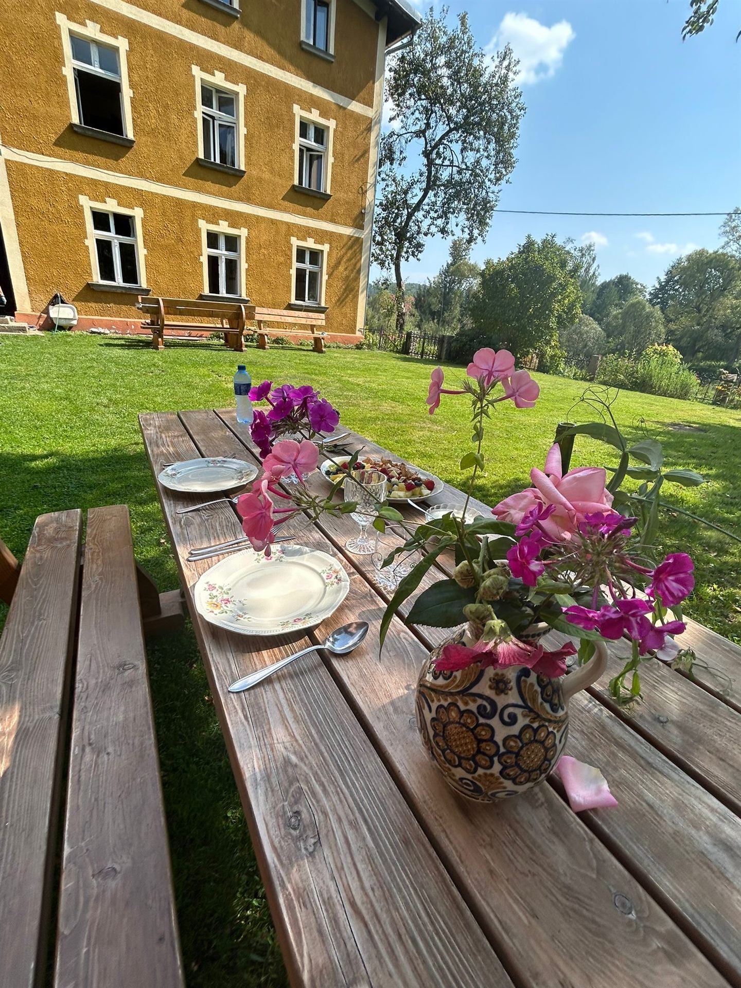 Picnic table laid with a bunch of flowers in the garden at Domstolat