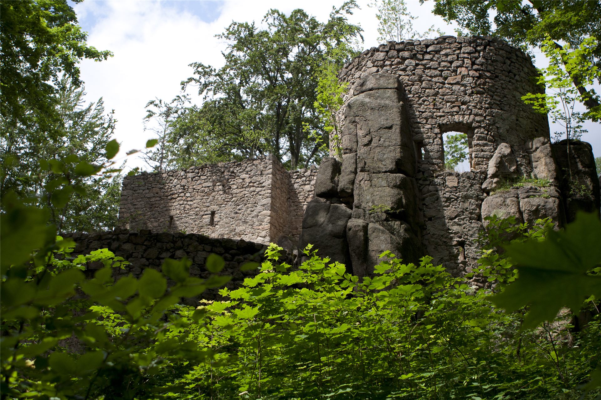 The stone ruins of Bolczów Castle among the rocks and greenery, within walking distance of Domstolat