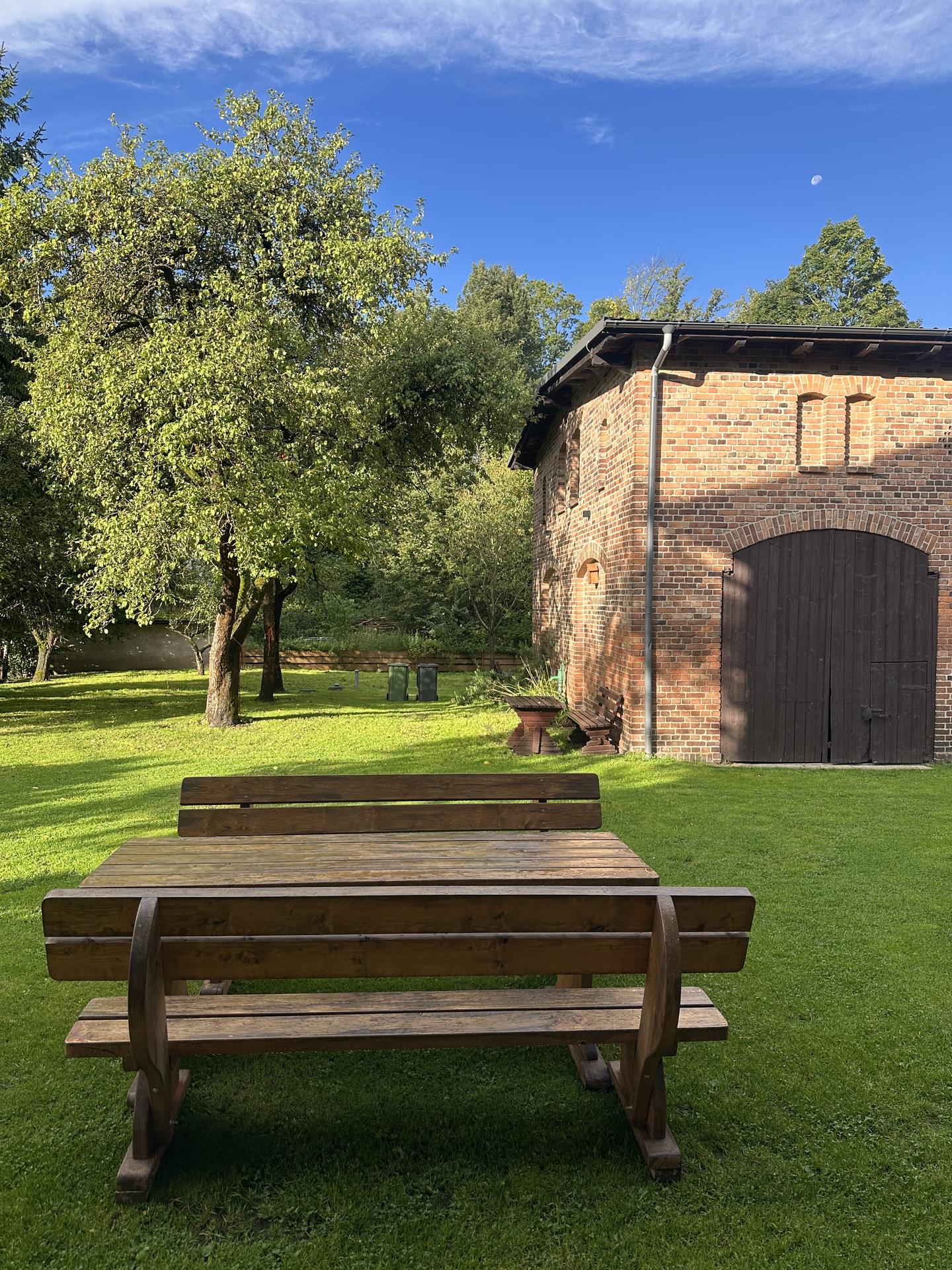 Wooden picnic table in the summer garden in front of the old brick barn