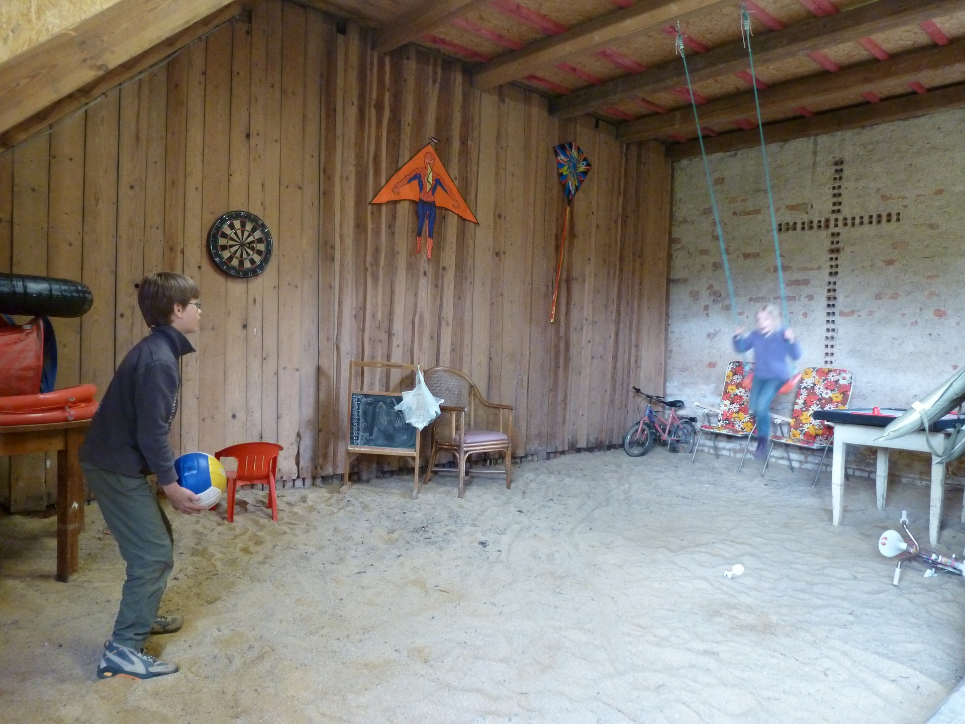 Children playing in the sandpit and on the swing in the covered play barn at Domstolat